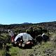two campers pack up their camp with tent among grass and lava field