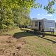 A white RV sits on a green lawn at a campsite in Ozark Campground.