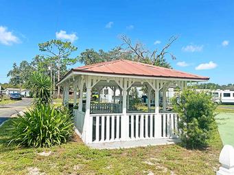 White gazebo/pavilion within the park — illustrates outdoor gathering amenity and visible RVs in the background indicating on-property location.