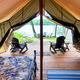 Glamping tent interior facing the lake with deck and chairs — highlights lakeside glamping accommodations (site glamping image).