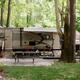Indian Springs Campground & Water Park - Family enjoying the new Splash Springs Floating Water Park with water slide, beach area, and scenic fishing lakes in a serene forest setting. Perfect for camping, fishing, and water fun near Fort Wayne.