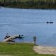 Two people in a canoe on a calm lake with a dock and pedal boats.