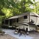 RV campsite photo (fifth-wheel, patio setup) from the site gallery — useful depiction of typical RV pitch and guest setup.