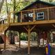 Close-up view of the same elevated cabin/treehouse showing deck furniture, hammocks and play equipment — useful detailed image of the property’s unique rental accommodation.
