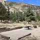 campsite with picnic table and fire pit with blue sky and mountains in background.