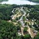 Aerial view showing campground layout with RVs/cabins, internal roads and nearby lake — good overall property overview matching site cover photo.