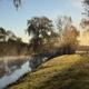 Wide view of the property's pond at sunrise with dock/structure and grassy shoreline — clear scenic feature shown on the site's 'Book Tour' page, good overview of on-site water feature and grounds.