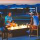 Evening photo of guests around a built-in firepit with RVs and mountains in background — shows communal amenity and evening atmosphere on the resort grounds (used in amenities section).