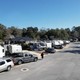 Wide-angle view of an RV row and campground circulation road, showing site spacing and surrounding vegetation — matches gallery images of the property.