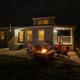 Night view of a cabin or rental unit with people around a firepit on a concrete patio — highlights on-site cabin lodging and evening amenities; image appears in the campground’s Ways to Stay section.