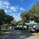 A row of rvs are parked in a parking lot surrounded by trees.