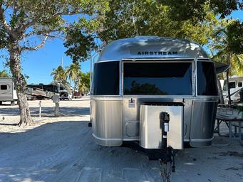 External view of an Airstream travel trailer parked under a tree at Big Pine Key RV Park in Florida