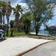 Sandy shoreline and palm trees with dock/pavilion visible — good scenic view of property shoreline and waterfront features (from homepage/amenities images).
