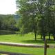 Open grass area with a pond and fence — shows on-site water feature and scenic grounds (About page imagery of property landscape).