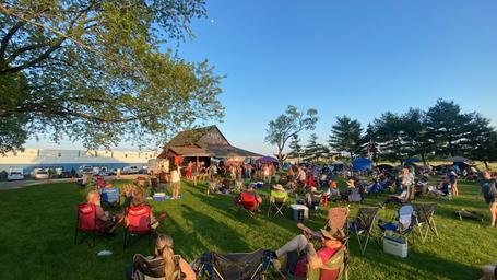 Wide scene of campground grounds with people, tents and pavilion area (social image on homepage). Shows activity and how the grounds are used during events.