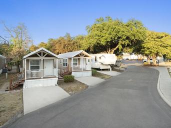 Ground-level shot showing guest cabins/cottages at the resort with adjacent RV spaces and mature trees — useful to show non-RV accommodation and onsite landscape.