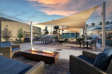 Outdoor lounge/firepit seating area with shade sails and tables — shows another on-site gathering space and resort amenities shown on the site.