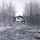 Black and white photo of Koknuk Cabin with leafless trees surrounding it