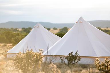 Close-up of bell tent peaks set in the landscape with distant hills — useful as an iconic image of the glamping tents and surrounding scenery at the property (sourced from the site).