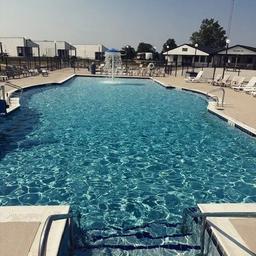 Large outdoor swimming pool with deck chairs and fencing — good depiction of the resort’s main pool facility as presented on the site.