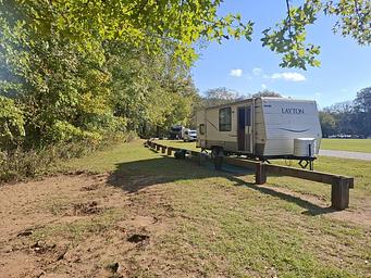 A white RV sits on a green lawn at a campsite in Ozark Campground.