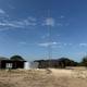 Wide outdoor shot including buildings, a large metal water tank and a tall communications tower — useful to show infrastructure and scale of the campground site.