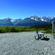A rv is parked in a gravel lot with mountains in the background.
