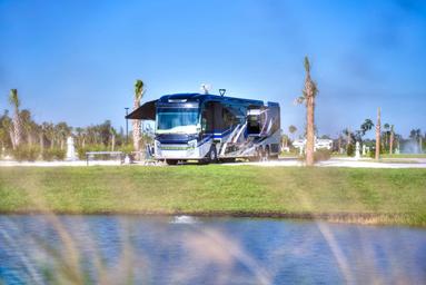 RV parked at a lakeside site with palm trees and utility pedestals visible — demonstrates RV site quality and waterfront setting (gallery / RV park imagery).