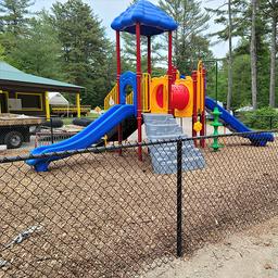 Playground structure within a fenced area on the campground grounds — highlights family amenities and kid-friendly facilities (photogallery image).