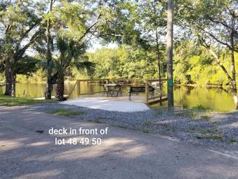 Concrete deck at waterfront lots #48–50 looking over the river with picnic seating — from the site’s lot photos and illustrates a typical waterfront campsite feature.