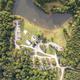 Clear aerial/drone overview of the campground showing lake, RV sites, pool area, roads and buildings — visible layout matches property grounds and is hosted on the campground site pages (Stay / homepage imagery).