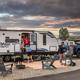 Clear daytime photo of an RV site with patio area, chairs, grill and vehicles — shows the campground’s RV accommodations and site layout; sourced from the campground’s Ways to Stay gallery on the property page.
