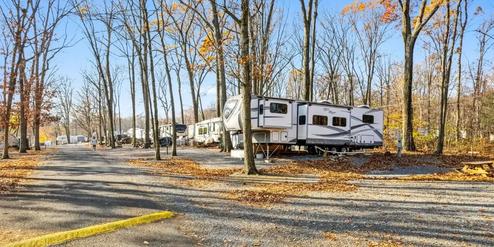 Large fifth-wheel trailer nestled among autumn trees