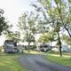 Campground with RVs and trailers parked among trees on a sunny day