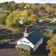 Aerial overview of the campground showing the central store/church building, RV sites, roads, tennis/pickleball courts and surrounding grounds — strong overview of property layout (used on homepage/slide background).