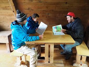 Three people at a wooden table in a Berg Bay cabin
