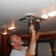 RV repair technician fastening a ceiling  vent with a power drill inside a camper