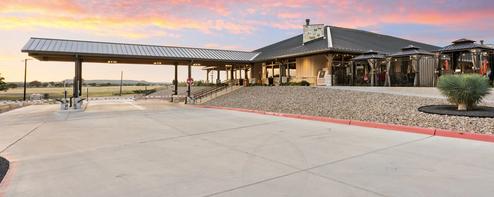 Exterior panorama of the clubhouse/building and adjacent outdoor areas at sunset — highlights the main clubhouse and gathering spaces used by guests (gallery hero/images show clubhouse).