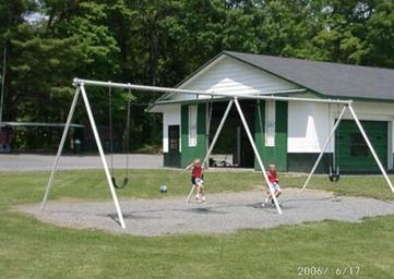 Playground swings in front of a facility building — shows on-site recreation and family facilities (from the Camping photo gallery page).