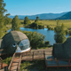 Geodesic dome in front of stream and Teton Mountains.