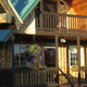 Exterior photo of a cabin with porch, hanging baskets and surrounding trees — from the site header/home page, shows cabin lodging appearance.