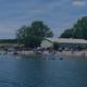Wide waterfront/beach scene with buildings and swimmers along shore — shows on-site lake beach and facilities (home hero background on site).