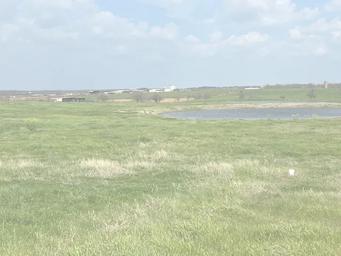 Wide countryside scene with pond and distant buildings — shows surrounding landscape and on-site open space visible on the home page.