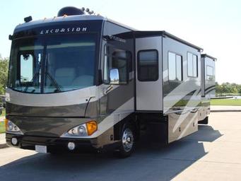 Well-lit front/side view of an Excursion motorhome with slide-out, parked on the property pavement; sourced from the site homepage showing fleet presentation (page: Motorhome Rentals and Service Center).