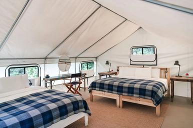 Interior view of a furnished glamping tent showing bed layout and finishes — useful to illustrate accommodations and tent interiors (labeled tent interior on site).
