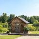 Frontal view of the same lakeside cabin and surrounding landscaping with wider framing — useful overview of cabin placement on the property (used as background/home header images).