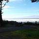 A campsite on a bluff overlooking the Pacific Ocean. The campsite has a paved parking spot as well as a picnic table and fire ring.