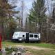 Travel trailer/RV site with a parked trailer among trees and campsite infrastructure visible — documents RV/trailer accommodations available at the campground.