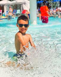 Close-up of a child splashing in a pool — highlights the onsite swimming/water play amenity and family-friendly atmosphere.