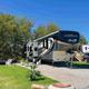 Premium RV lot with a parked fifth-wheel, patio area and landscaping — demonstrates typical campsite setup and guest space on the property.
